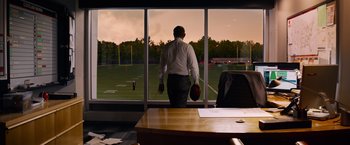 Movie still from “Draft Day” (2014), directed by Ivan Reitman – A man standing in front of an office window; Wide shot, Over the shoulder angle
