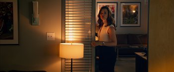 Movie still from “Draft Day” (2014), directed by Ivan Reitman – A woman standing in front of a window in a room; Medium shot, Over the shoulder angle