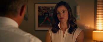 Movie still from “Draft Day” (2014), directed by Ivan Reitman – A woman standing in front of a picture of a baseball player; Close Up shot, Over the shoulder angle