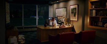 Movie still from “Draft Day” (2014), directed by Ivan Reitman – A man sitting at a desk in an office setting; Wide shot, High angle