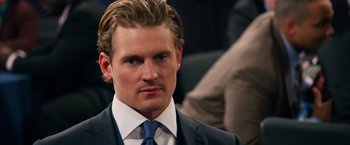 Movie still from “Draft Day” (2014), directed by Ivan Reitman – A person wearing a suit and tie; Close Up shot, Over the shoulder angle