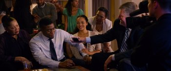 Movie still from “Draft Day” (2014), directed by Ivan Reitman – A group of people sitting in a living room; Medium shot, Over the shoulder angle