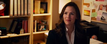 Movie still from “Draft Day” (2014), directed by Ivan Reitman – A woman wearing a suit and tie in a room; Close Up shot, Over the shoulder angle