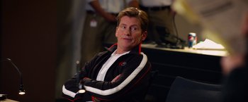 Movie still from “Draft Day” (2014), directed by Ivan Reitman – A man sitting in a chair with his arms crossed; Medium shot, Over the shoulder angle
