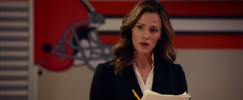 Movie still from “Draft Day” (2014), directed by Ivan Reitman – A woman in a black jacket is holding a notebook; Close Up shot, Over the shoulder angle