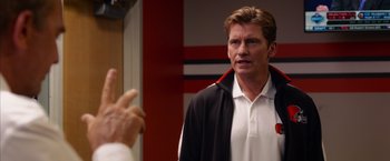 Movie still from “Draft Day” (2014), directed by Ivan Reitman – A man with a stethoscope around his neck; Close Up shot, Over the shoulder angle