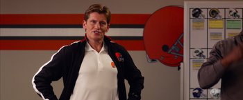 Movie still from “Draft Day” (2014), directed by Ivan Reitman – A man standing in front of a football helmet; Medium shot, High angle