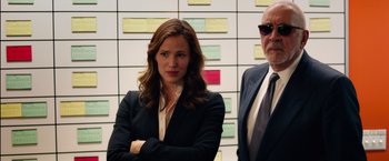 Movie still from “Draft Day” (2014), directed by Ivan Reitman – A woman standing next to a man in a suit and tie; Medium shot, Over the shoulder angle