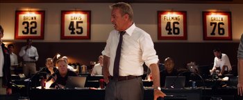 Movie still from “Draft Day” (2014), directed by Ivan Reitman – A man in a white dress shirt and a tie; Medium shot, Over the shoulder angle