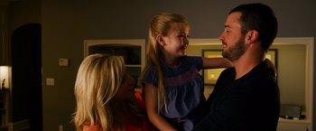 Movie still from “Draft Day” (2014), directed by Ivan Reitman – A little girl sitting on a woman's lap; Medium shot, Over the shoulder angle