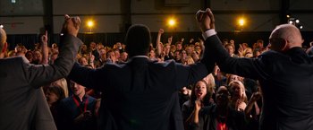 A crowd of people in a room with one man raising his hand
