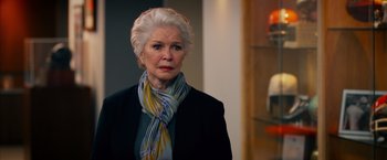 Movie still from “Draft Day” (2014), directed by Ivan Reitman – An older woman wearing a black jacket and a colorful scarf; Close Up shot, Over the shoulder angle