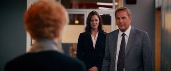 Movie still from “Draft Day” (2014), directed by Ivan Reitman – A woman and a man standing next to each other in front of another man; Medium shot, Over the shoulder angle
