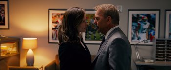 Movie still from “Draft Day” (2014), directed by Ivan Reitman – A man and a woman standing next to each other in a room; Close Up shot, Over the shoulder angle