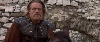 Movie still from “DragonHeart” (1996), directed by Rob Cohen – A person on a horse near a stone wall; Close Up shot, Low angle