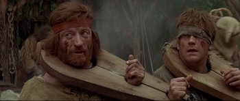 Movie still from “DragonHeart” (1996), directed by Rob Cohen – A man with long hair and a red beard holding a wooden plank; Close Up shot, Low angle