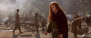 Movie still from “DragonHeart” (1996), directed by Rob Cohen – A red headed woman in a green robe walking in the dirt; Medium shot, Low angle