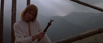 Movie still from “DragonHeart” (1996), directed by Rob Cohen – A woman holding a wooden object in front of a mountain; Medium shot, Low angle