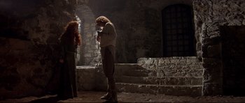 Movie still from “DragonHeart” (1996), directed by Rob Cohen – A man standing next to a woman in a room; Wide shot, Low angle