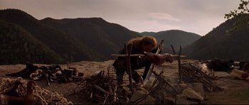 Movie still from “DragonHeart” (1996), directed by Rob Cohen – A man is working in the wilderness with a knife; Wide shot, Low angle