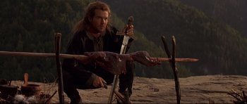 Movie still from “DragonHeart” (1996), directed by Rob Cohen – A man holding a sword in a field with a dead animal; Medium shot, Low angle