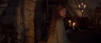 Movie still from “DragonHeart” (1996), directed by Rob Cohen – A woman with long curly red hair holding a candle; Medium shot, High angle
