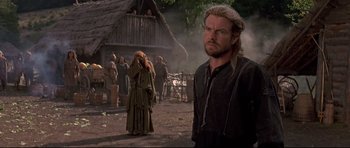 Movie still from “DragonHeart” (1996), directed by Rob Cohen – A man standing next to a woman in front of a building; Medium shot, Over the shoulder angle