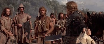 Movie still from “DragonHeart” (1996), directed by Rob Cohen – A group of men standing next to each other holding axes; Medium shot, Over the shoulder angle