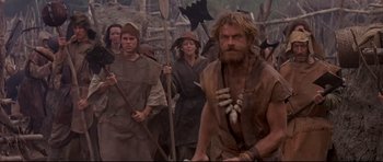 Movie still from “DragonHeart” (1996), directed by Rob Cohen – A group of people are gathered together in the woods; Medium shot, Over the shoulder angle