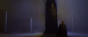 Movie still from “DragonHeart” (1996), directed by Rob Cohen – A statue of a person in a dark room; Wide shot, Low angle