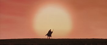 Movie still from “DragonHeart” (1996), directed by Rob Cohen – A person riding a horse in a field at sunset; Extreme Wide shot, Low angle