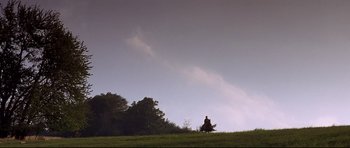 Movie still from “DragonHeart” (1996), directed by Rob Cohen – A person riding a horse in a grassy field; Extreme Wide shot, Low angle