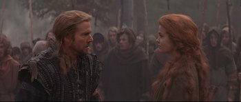 Movie still from “DragonHeart” (1996), directed by Rob Cohen – A man and a woman in medieval garb in a crowd; Close Up shot, Over the shoulder angle