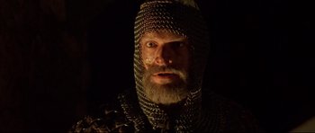 Movie still from “DragonHeart” (1996), directed by Rob Cohen – A man with a beard and a chain mail helmet; Close Up shot, Low angle
