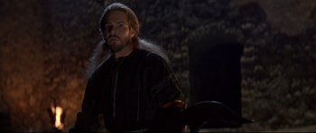 Movie still from “DragonHeart” (1996), directed by Rob Cohen – A man with long hair and a beard is standing in the dark; Close Up shot, Low angle