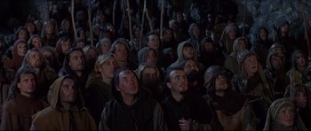 Movie still from “DragonHeart” (1996), directed by Rob Cohen – A group of people wearing hoods and holding wooden sticks; Wide shot, High angle