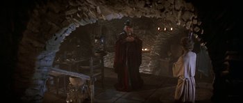 Movie still from “Dragonslayer” (1981), directed by Matthew Robbins – A man dressed as a wizard is standing in a cave; Wide shot, High angle