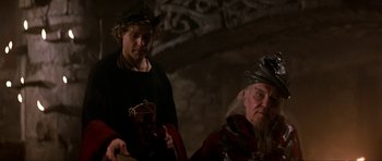 Movie still from “Dragonslayer” (1981), directed by Matthew Robbins – Two men in medieval garb are sitting in a cave; Close Up shot, Over the shoulder angle