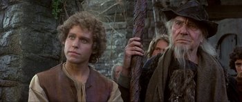 Movie still from “Dragonslayer” (1981), directed by Matthew Robbins – A group of people standing next to each other in a forest; Medium shot, Low angle