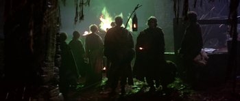Movie still from “Dragonslayer” (1981), directed by Matthew Robbins – A group of people standing in front of a bonfire; Wide shot, Low angle
