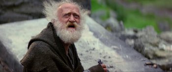 Movie still from “Dragonslayer” (1981), directed by Matthew Robbins – An old man with a beard is sitting on the ground; Close Up shot, Low angle