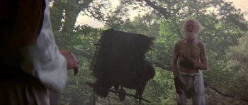 Movie still from “Dragonslayer” (1981), directed by Matthew Robbins – A man standing next to a tree in the woods; Wide shot, Low angle