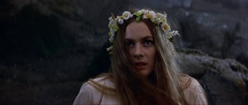 Movie still from “Dragonslayer” (1981), directed by Matthew Robbins – A woman with long brown hair wearing a flower crown; Close Up shot, Over the shoulder angle