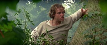Movie still from “Dragonslayer” (1981), directed by Matthew Robbins – A man standing next to a tree in the woods; Close Up shot, Low angle