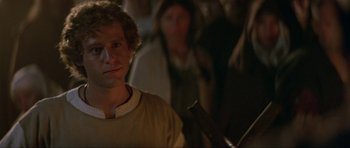 Movie still from “Dragonslayer” (1981), directed by Matthew Robbins – A man in a brown shirt is looking at the camera; Close Up shot, Over the shoulder angle