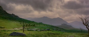 Movie still from “Dragonslayer” (1981), directed by Matthew Robbins – A view of a grassy field with a mountain in the background; Extreme Wide shot, Low angle