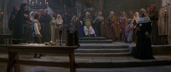 Movie still from “Dragonslayer” (1981), directed by Matthew Robbins – A group of people standing around a table; Wide shot, High angle