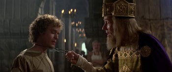 Movie still from “Dragonslayer” (1981), directed by Matthew Robbins – A man is holding a pair of scissors in his hand; Close Up shot, Over the shoulder angle