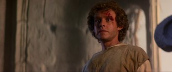 Movie still from “Dragonslayer” (1981), directed by Matthew Robbins – A person with a knife on his head; Close Up shot, Low angle