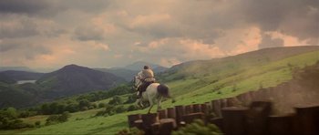 Movie still from “Dragonslayer” (1981), directed by Matthew Robbins – A man riding a horse down a grassy hill; Extreme Wide shot, Low angle